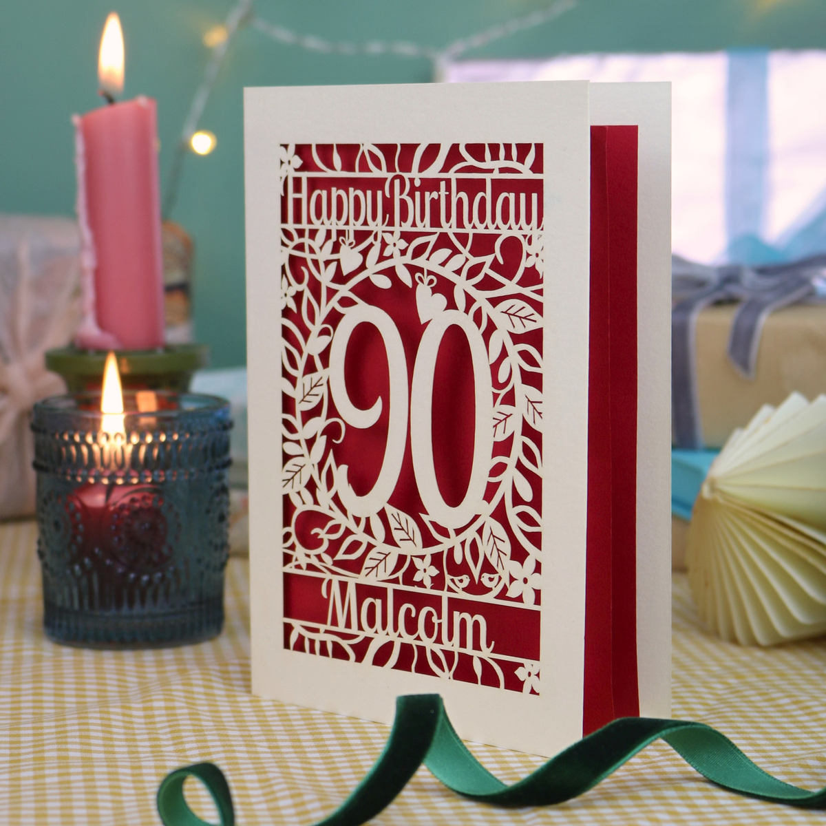 A cream laser cut 90th birthday card with leaf border, decorative '90' in the centre and text above, 'Happy Birthday'. The 90th birthday card is personalised at the bottom with the name 'Malcolm'. The birthday card is cream with a deep red paper insert. 