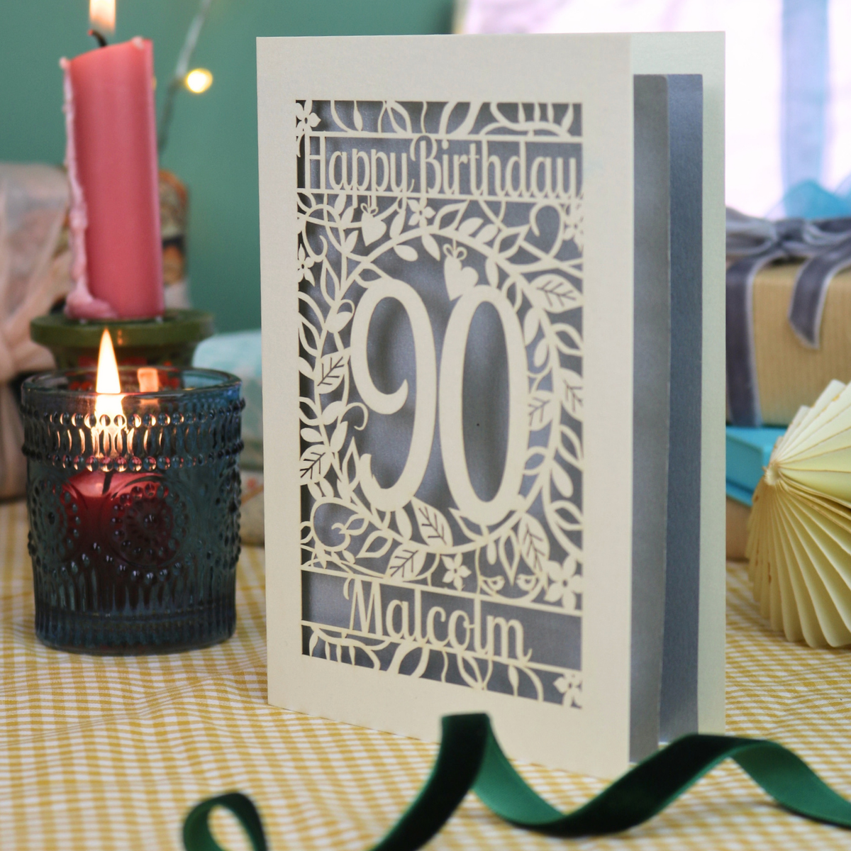 A cream laser cut 90th birthday card with leaf border, decorative '90' in the centre and text above, 'Happy Birthday'. The 90th birthday card is personalised at the bottom with the name 'Malcolm'. The birthday card is cream with a silver paper insert. 