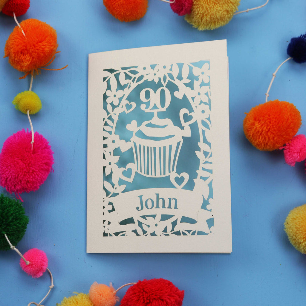 Decorative special 90th birthday card with '90' and 'John' on a blue background with colourful pom-poms.