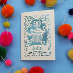 Decorative special 90th birthday card with '90' and 'John' on a blue background with colourful pom-poms.