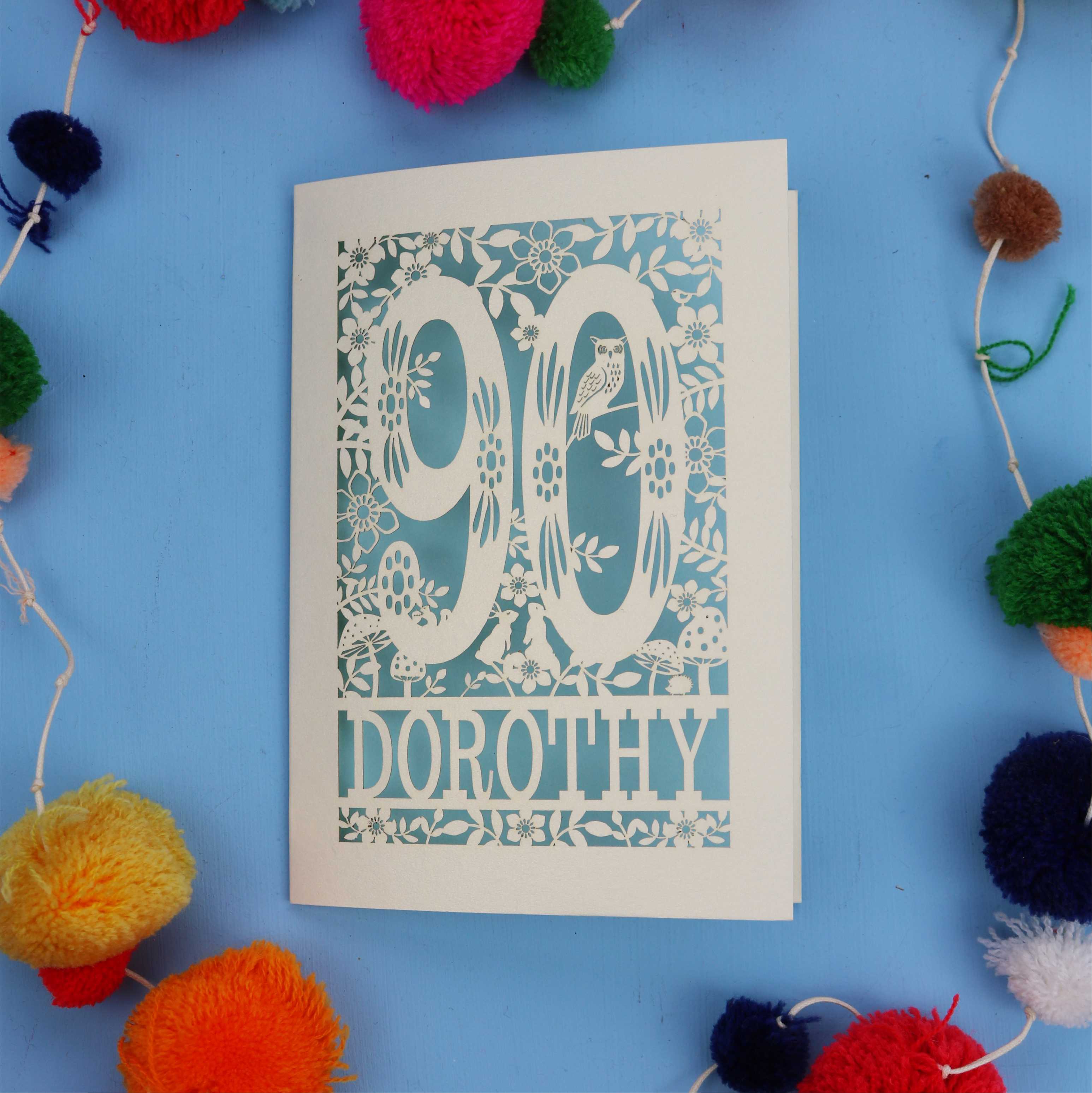 90th Birthday Card with '90 Dorothy' design on a blue background with colourful pom-poms.