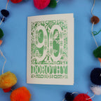 90th Birthday Card with '90 Dorothy' design on a blue background with colourful pom-poms.