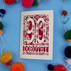 90th Birthday Card with '90 Dorothy' design on a blue background with colourful pom-poms.