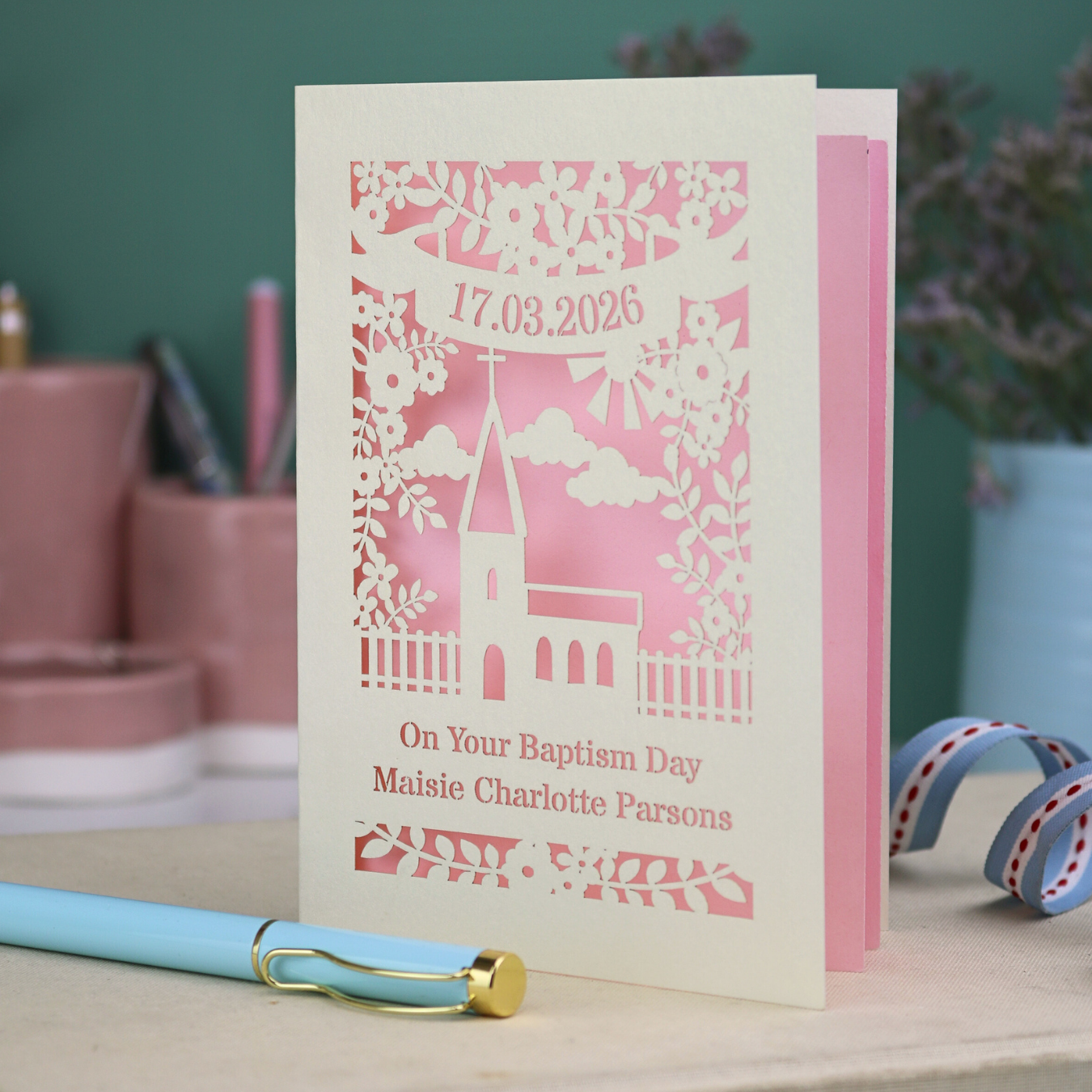 A laser cut Baptism card with floral cut out church design, a banner with date in stencil font and text "On your Baptism Day, Maisie Charlotte Parsons"