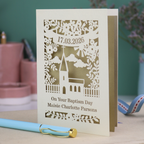 A laser cut Baptism card with floral cut out church design, a banner with cut out date in stencil font and text "On your Baptism Day, Maisie Charlotte Parsons"