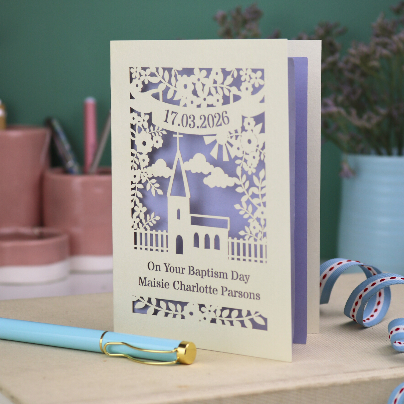 A laser cut Baptism card with floral cut out church design, a banner with cut out date in stencil font and text "On your Baptism Day, Maisie Charlotte Parsons"