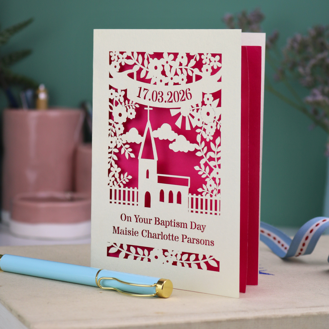 A laser cut Baptism card with floral cut out church design, a banner with cut out date in stencil font and text "On your Baptism Day, Maisie Charlotte Parsons"