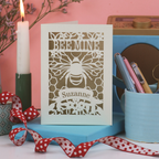 Laser cut Valentine's Card with bee design and 'Bee Mine' text on a pink background with candles and stationery.