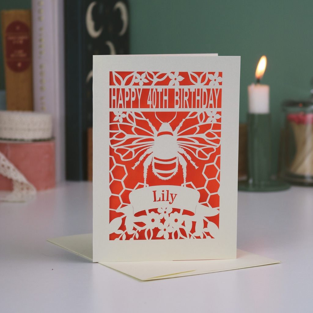 Birthday card with bee design and 'Happy 40th Birthday, Lily' text on a white surface.