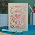 A laser cut Mother's Day card with intricate floral design with heart in the centre and the text "To the best mum in the whole world" cut out of two banners