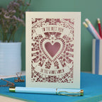 A laser cut card with intricate floral design with heart in the centre and the text "To the best mum in the whole world" cut out of two banners