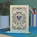 A laser cut card with intricate floral design with heart in the centre and the text "To the best mum in the whole world" cut out of two banners