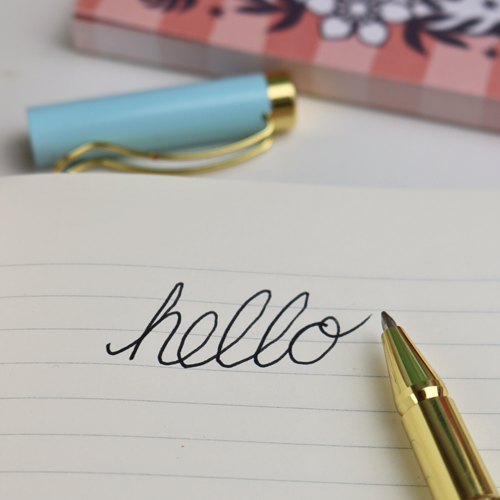 A handwritten 'Hello' on lined paper with a ballpoint pen