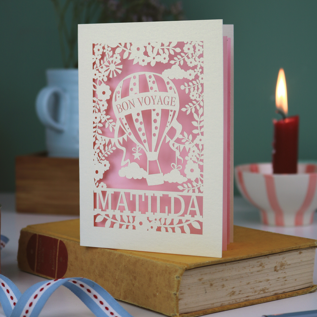 Decorative card with 'Bon Voyage Matilda' design on a book with a candle and cup in the background.