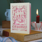Decorative card with 'Bon Voyage Matilda' design on a book with a candle and cup in the background.