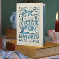 Laser-cut card with hot air balloon design on a book with a green background