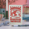 A laser cut Boyfriend Valentine's card with globe design and the words "Happy Valentine's Day to the best boyfriend in the world", on a desk with stationery items and pinkbackground