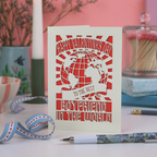 A laser cut Boyfriend Valentine's card with globe design and the words "Happy Valentine's Day to the best boyfriend in the world", on a desk with stationery items and pinkbackground