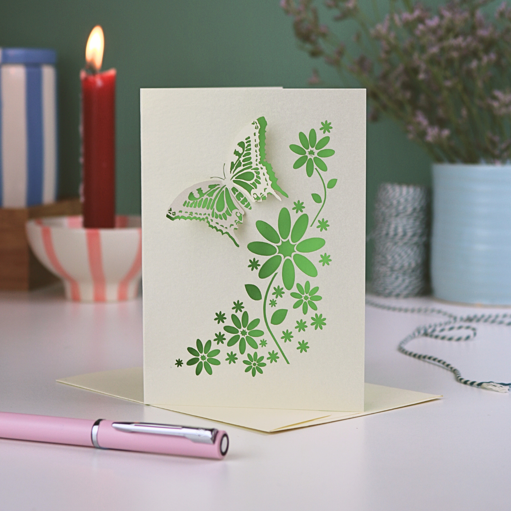 Mother's Day Butterfly Card with green butterfly and floral design on a table with candles and flowers in the background
