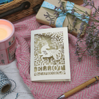 A laser cut Capricorn birthday card on pink background with candle, pen and gift. 