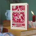 Decorative birthday card with unicorn carousel design and personalised with a name, standing on a book with a blurred background