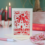 Papercut birthday Card with castle design and 'Ella Mae' text on a table with candles and books.