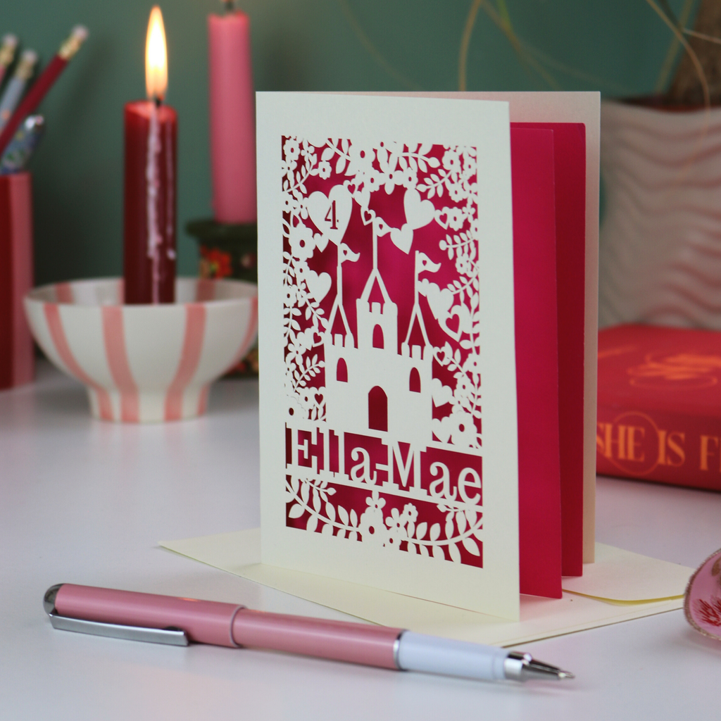Decorative Castle birthday card with cut-out design on a table with candles and a pen.