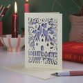 Laser-cut birthday card with castle design on a table with candles and books in the background