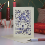 Laser-cut birthday card with castle design on a table with candles and books in the background