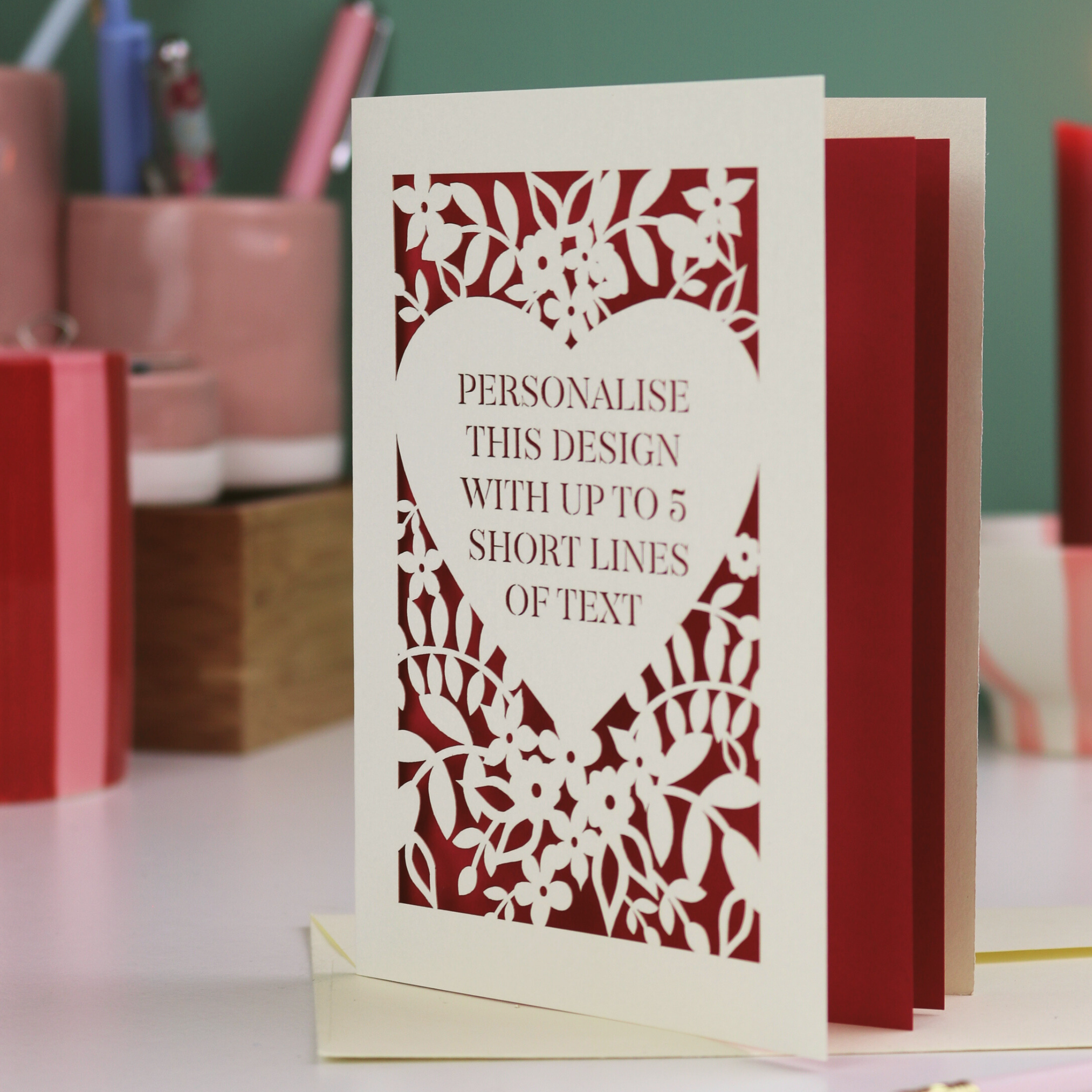 Laser-cut card with text on a desk with stationery items.