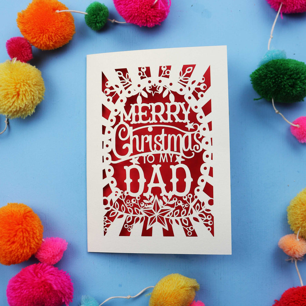 Dad Christmas card with 'Merry Christmas to my Dad' text on a blue background with colourful pom-poms.
