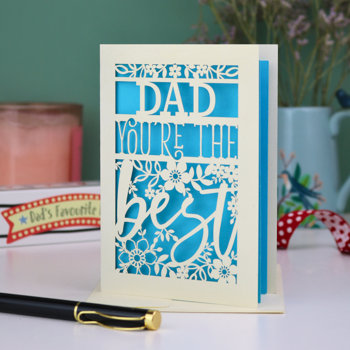 Special Father's Day Card with 'Dad, you're the best' text on a table with decorative items in the background