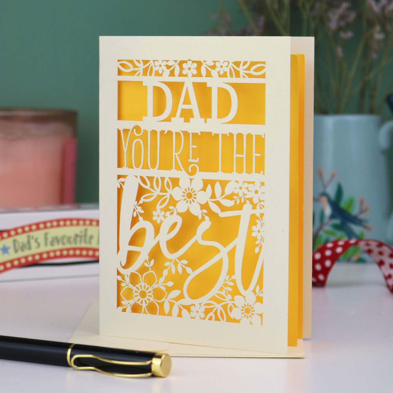 Father's Day Card with 'Dad, you're the best' text on a table with decorative items in the background