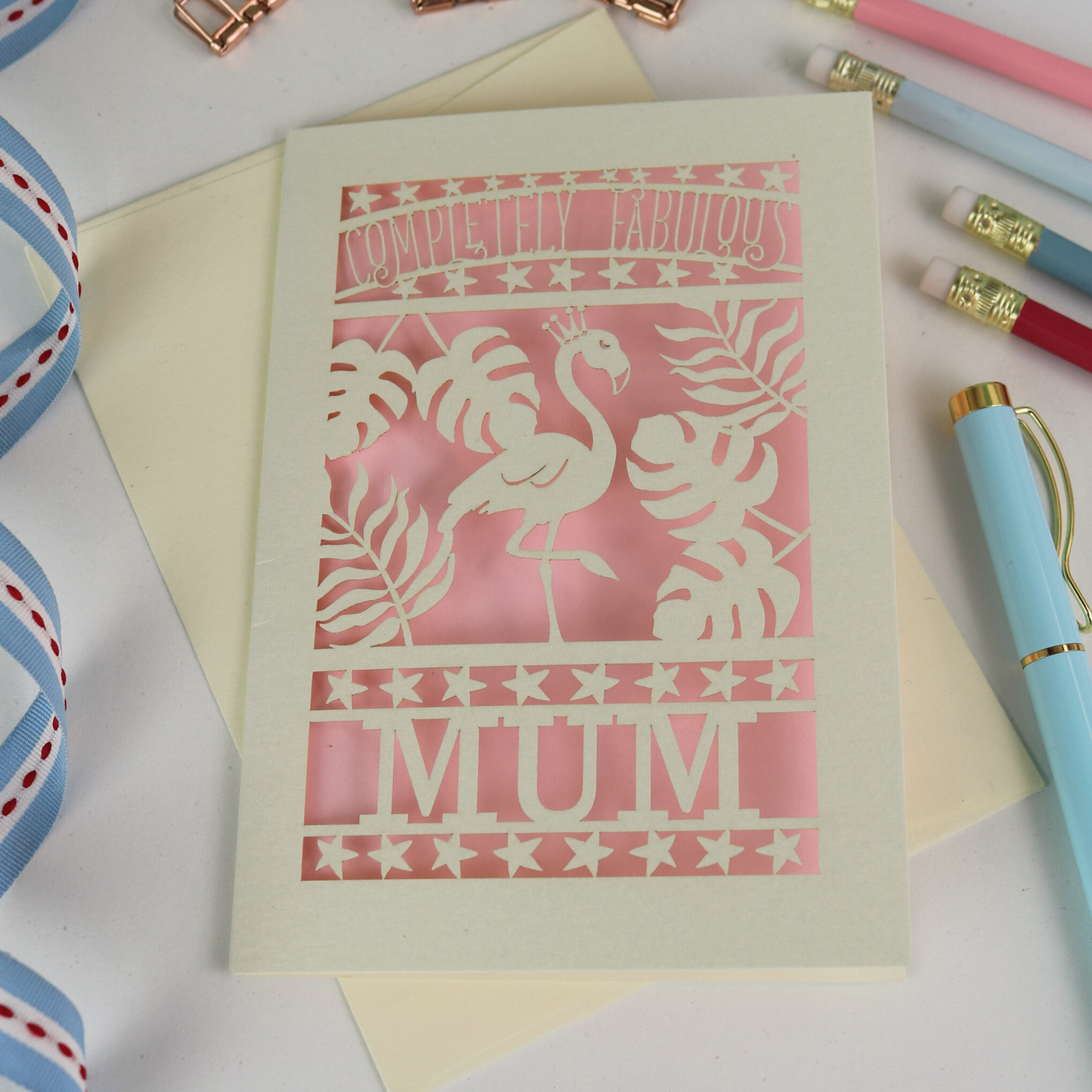 Greeting card with flamingo design and 'Completely Fabulous Mum' text on a desk with stationery items.