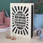 A laser cut sentimental Father's Day card with the cut out quote "Dad, a son's first hero, a daughter's first love"