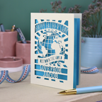 A laser cut Father's Day card with cream cut out card and a bright blue paper insert. Card has a globe design and the text "Happy Father's Day to the best dad in the world, love from" and is personalised with a name. 