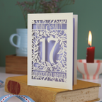 Laser cut anniversary Card personalised with '17 amazing years' design on a book with a candle and cup in the background