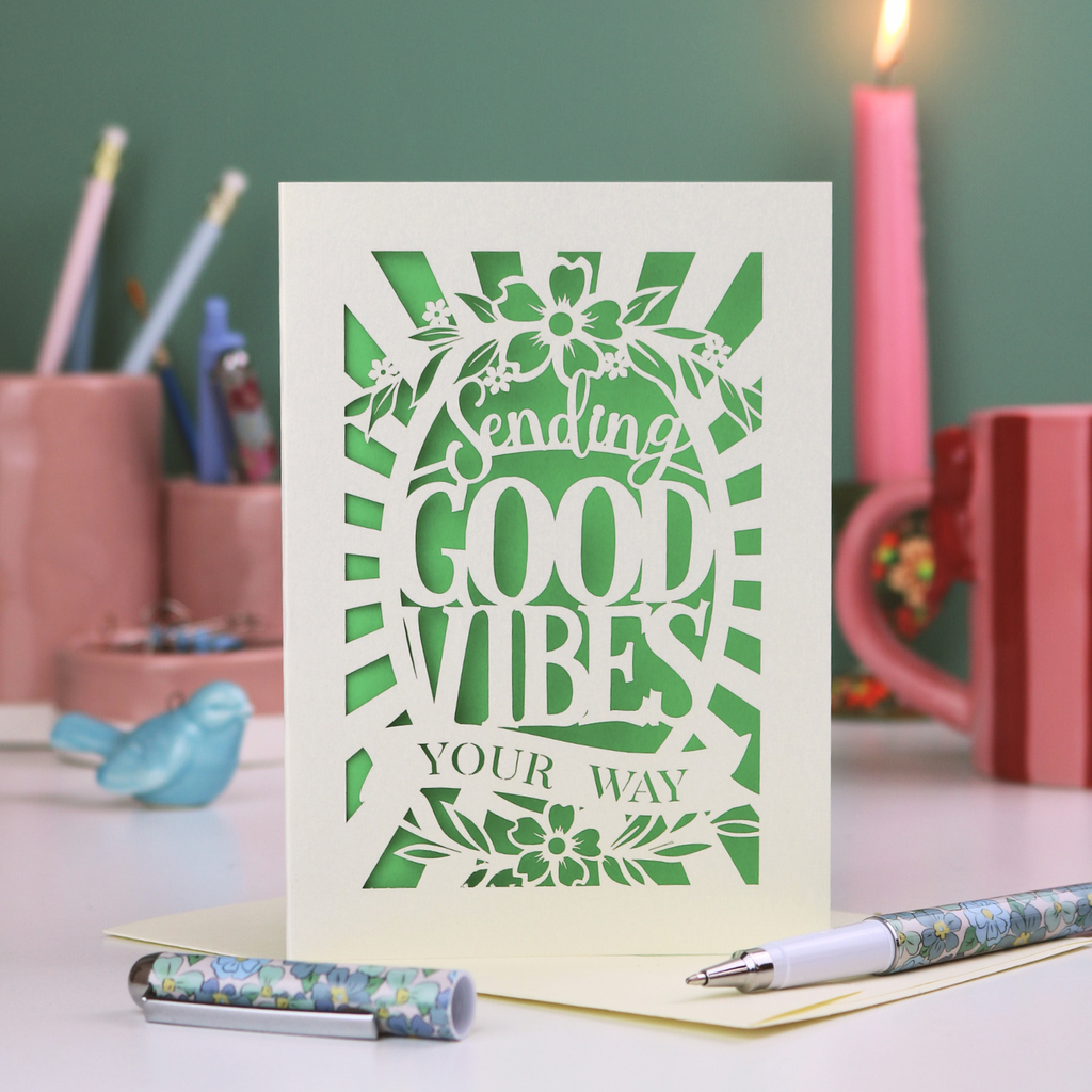 Laser cut Card with 'Sending Good Vibes Your Way' text on a desk with stationery items.