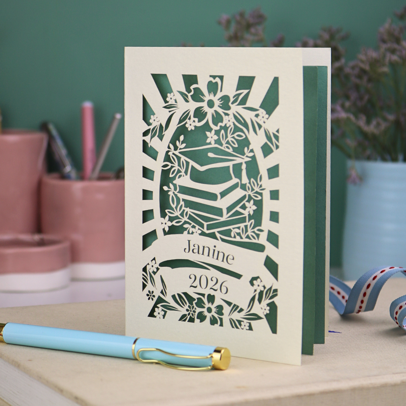 Personalised Laser cut graduation card with cap and book design, and personalised with a name and the year in stencil font in a banner