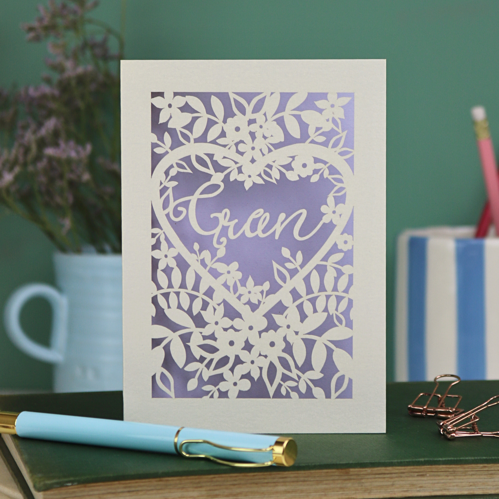Greeting card with floral design and 'Gran' text on a green surface with stationery items.