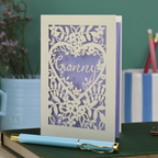 Laser cut Card with floral design and 'Granny' text on a desk with stationery items.