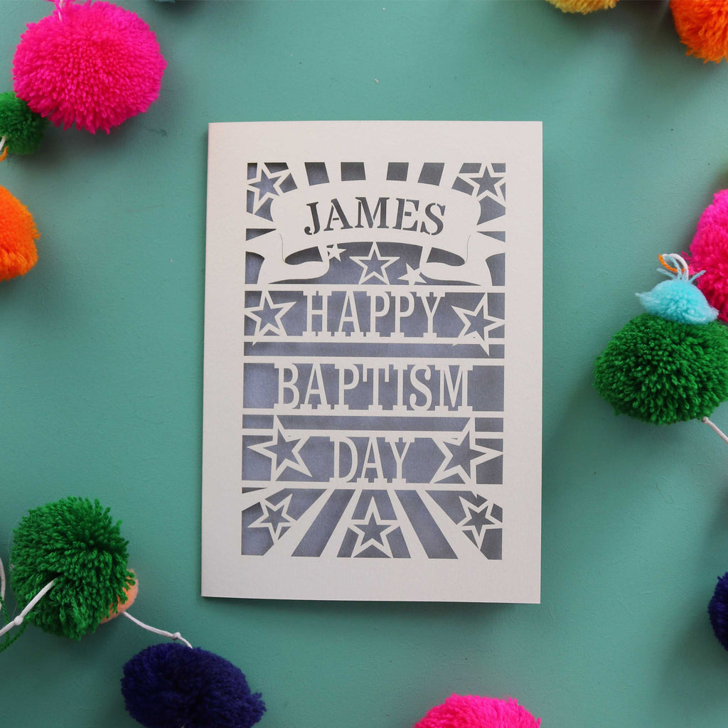 A laser cut Baptism card personalised with a first name in a banner and reads "Happy Baptism Day"