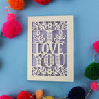 Cut out Valentine's Card with 'I LOVE YOU' design surrounded by colourful pom-poms on a blue background
