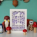 A personalised papercut 1st birthday card with a woodland animal theme, featuring cut-out shapes of an owl, rabbits, and a hedgehog, and the name 'THOMAS' in bold letters.