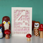 A personalised birthday card with a cut-out number 4 and woodland animal illustrations, placed on a table with toy animals and mushrooms.