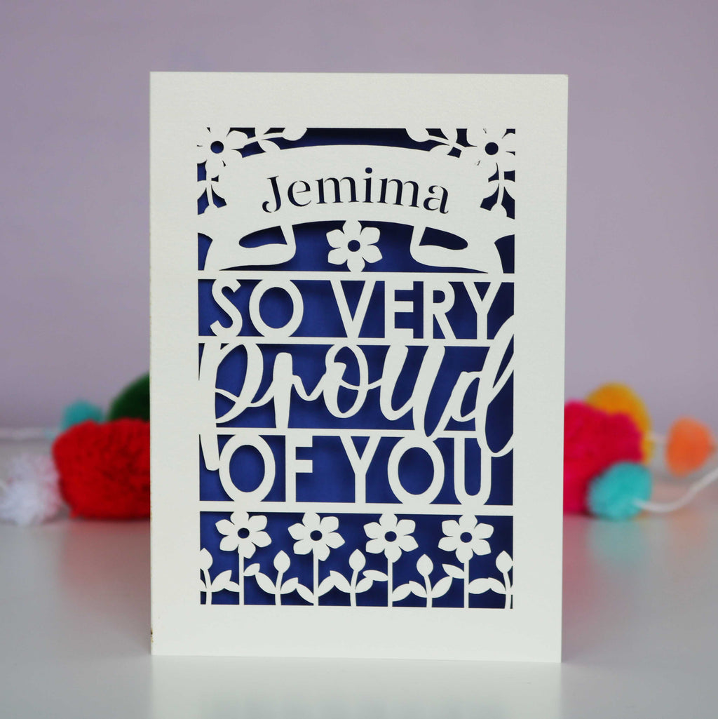A cut out congratulations card that is personalised with a name and reads "So very proud of you"