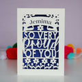A cut out congratulations card that is personalised with a name and reads "So very proud of you"