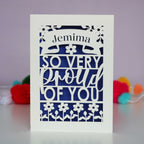 A cut out congratulations card that is personalised with a name and reads "So very proud of you"