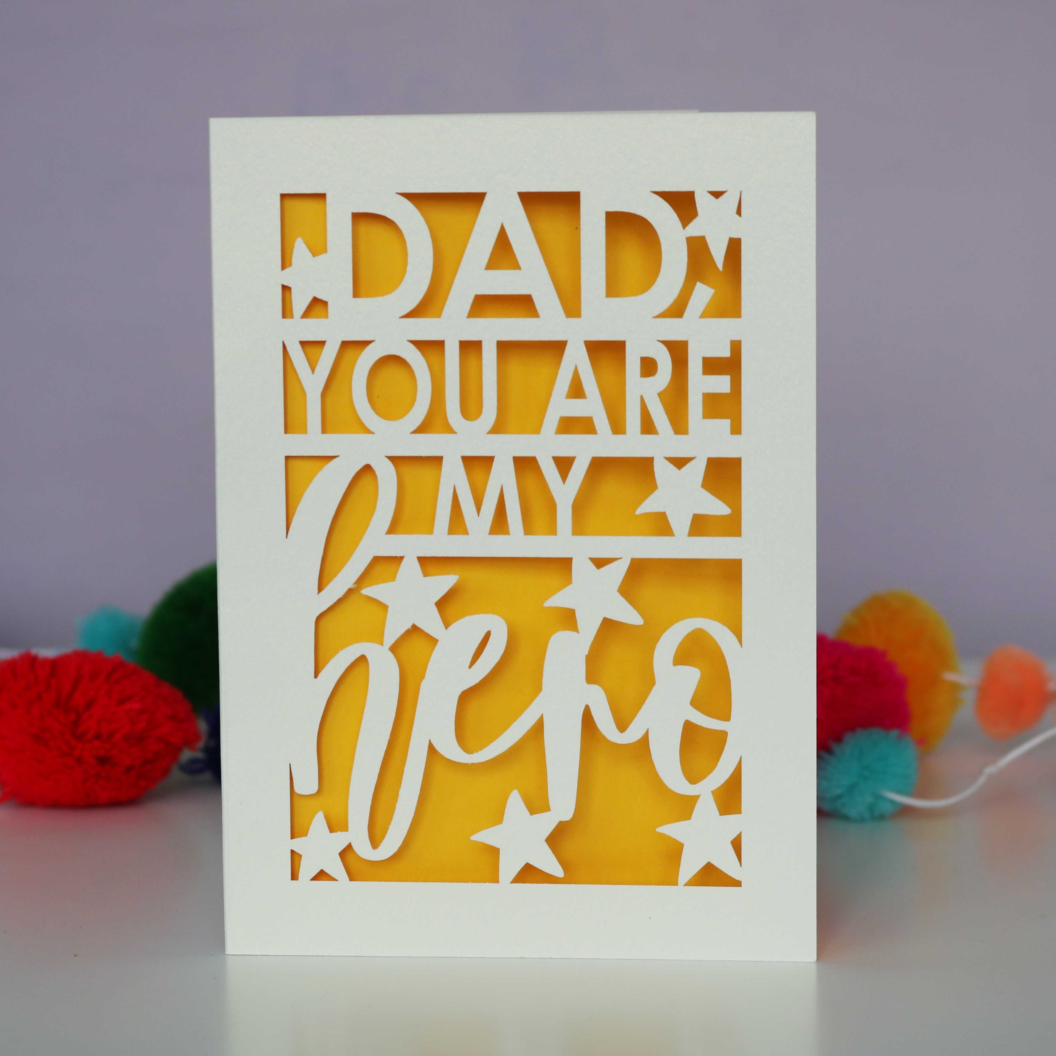 A cream and yellow papercut father's day card that says "Dad, You are my hero"