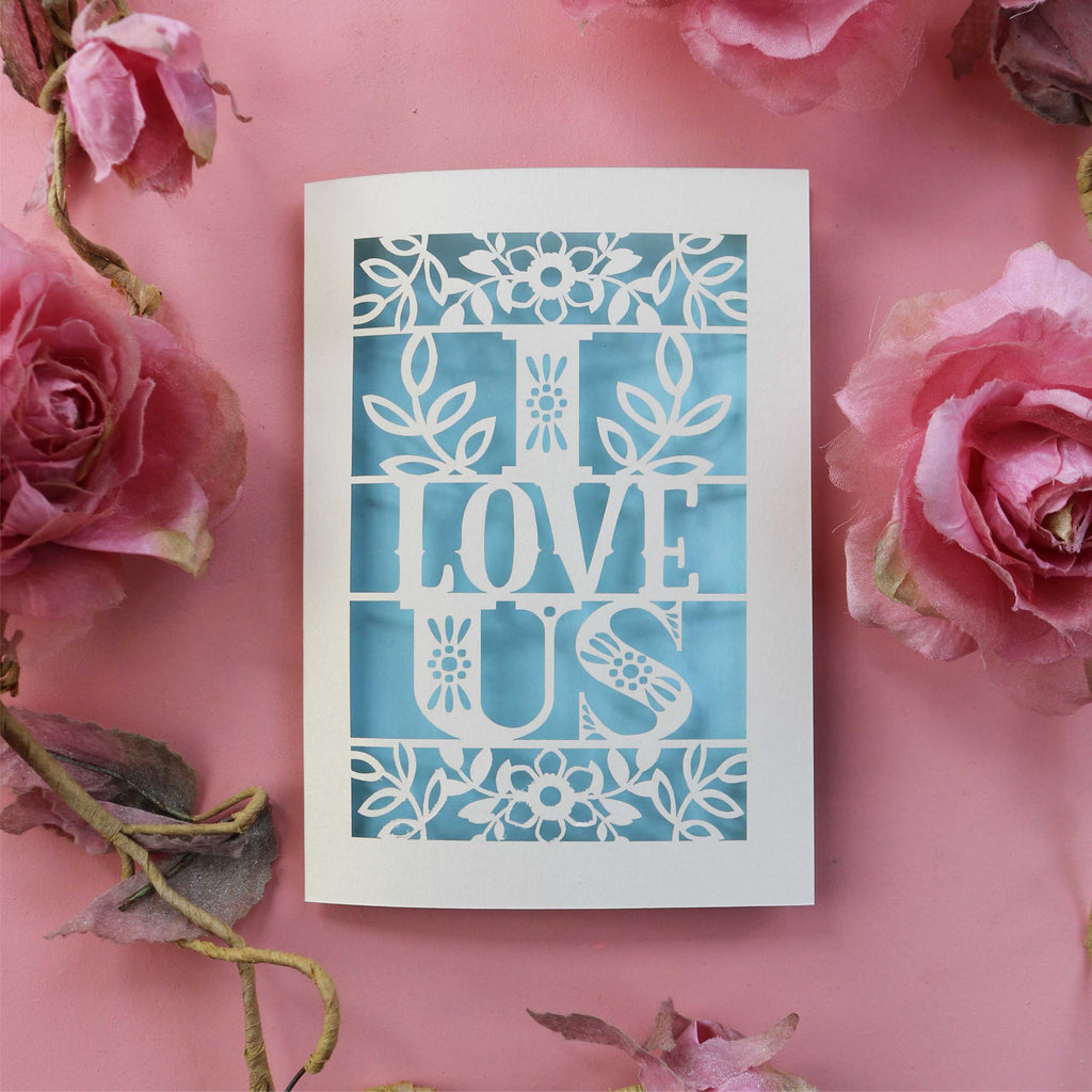 A papercut love Valentine's card with the words 'I LOVE US' cut out.